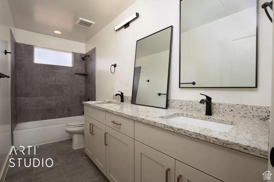 Full bathroom featuring toilet, double vanity, washtub / shower combination, and tile patterned floors