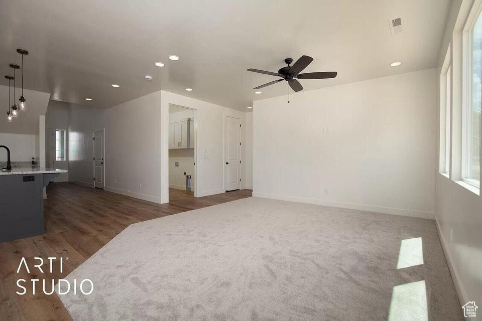 Unfurnished living room featuring ceiling fan, recessed lighting, baseboards, wood finished floors, and a sink