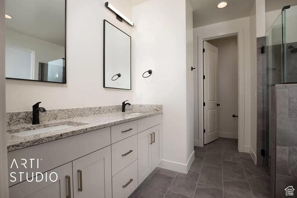 Full bathroom with a stall shower, baseboards, double vanity, and recessed lighting