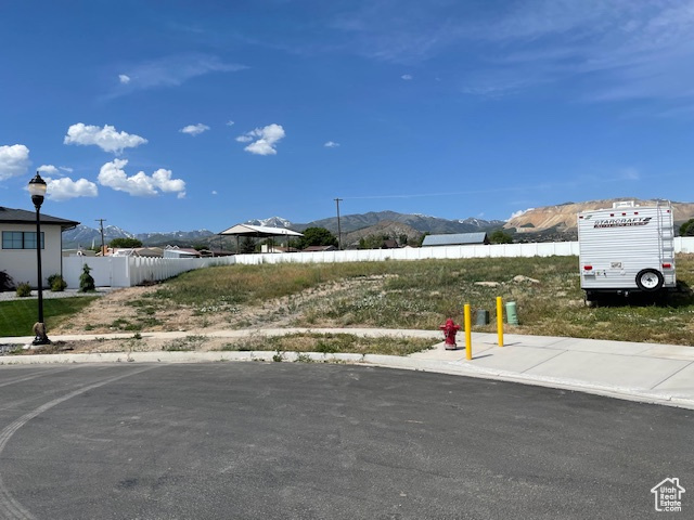 View of asphalt road with a mountain view, sidewalks, street lights, and curbs