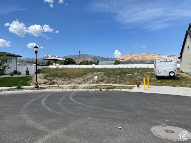 View of asphalt street with a mountain view, sidewalks, and street lighting