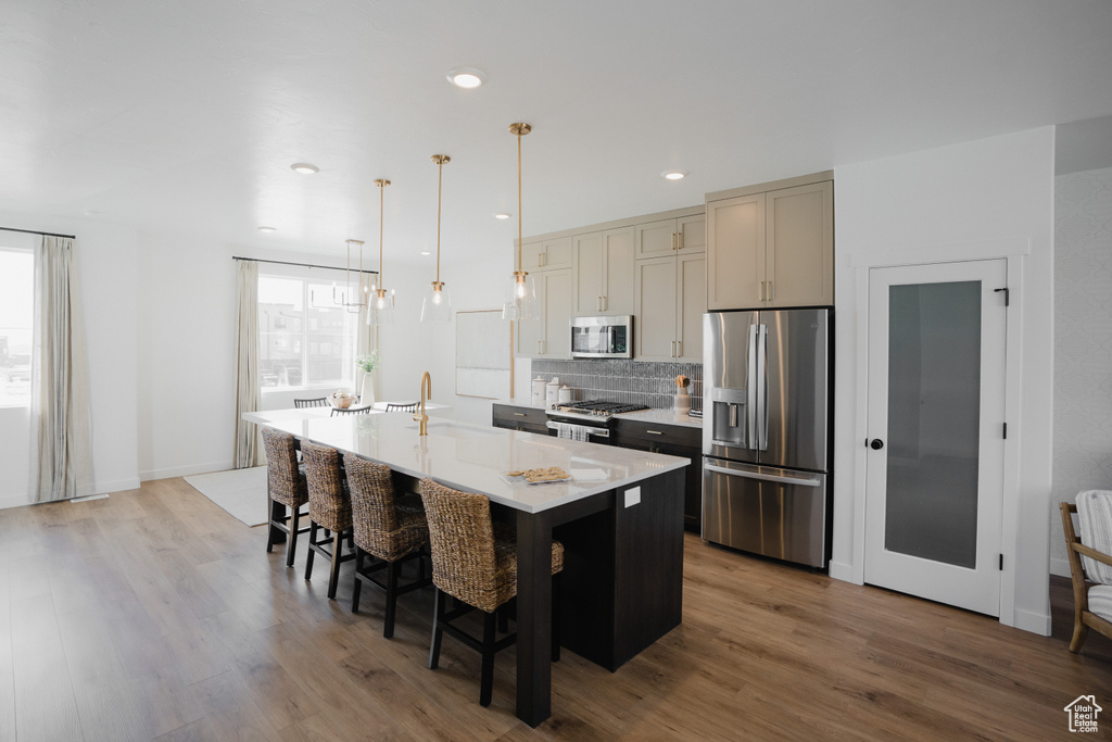 Kitchen featuring stainless steel appliances, healthy amount of natural light, an island with sink, a kitchen bar, and recessed lighting