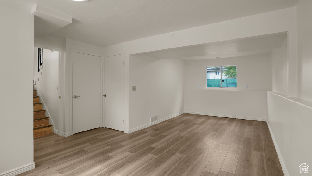Empty room featuring light wood-type flooring, baseboards, and stairway