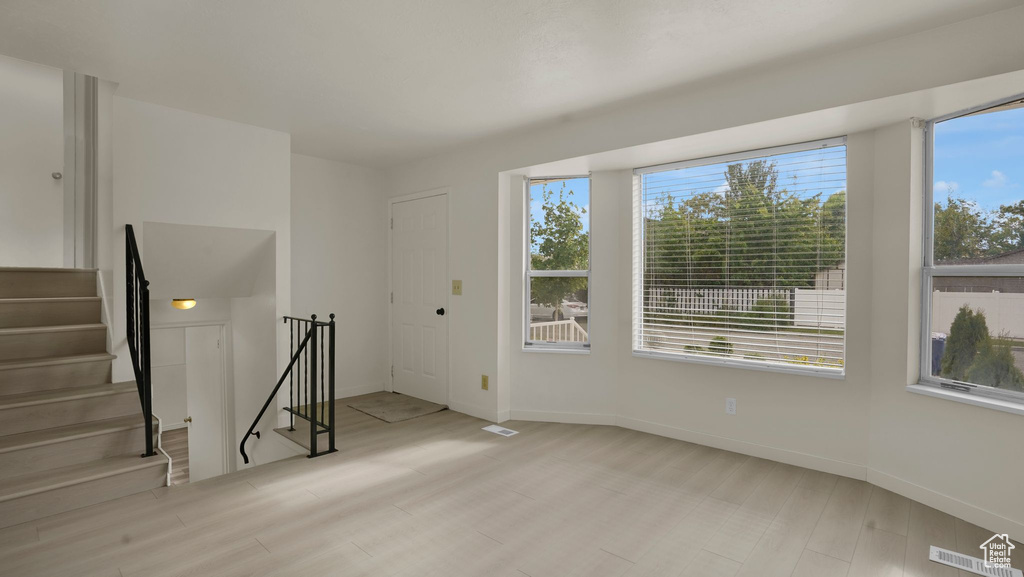 Unfurnished room featuring healthy amount of natural light, baseboards, stairway, and wood finished floors
