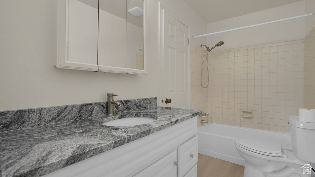 Bathroom with toilet, vanity, wood finished floors, and shower / bathtub combination
