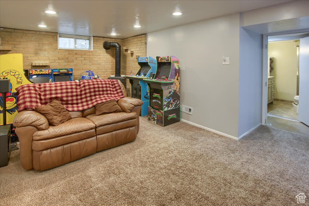 Carpeted living area featuring a wood stove, baseboards, recessed lighting, and brick wall