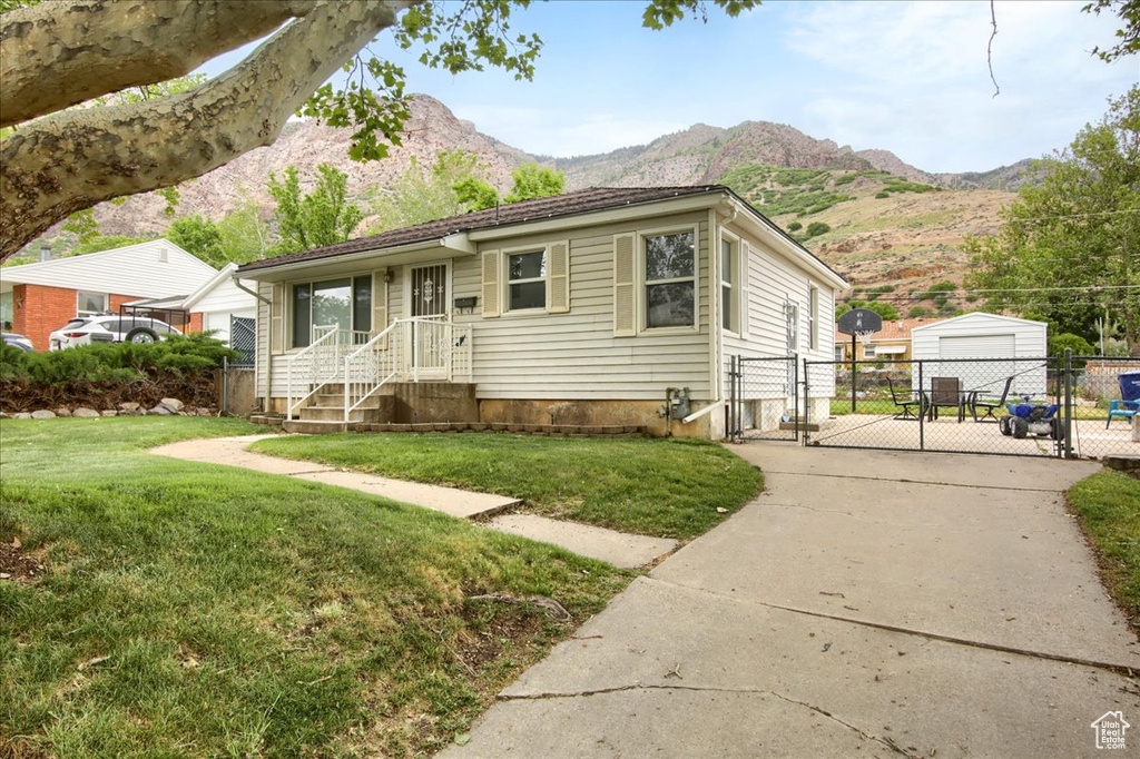 View of front of home with a gate, a mountain view, concrete driveway, and a detached garage