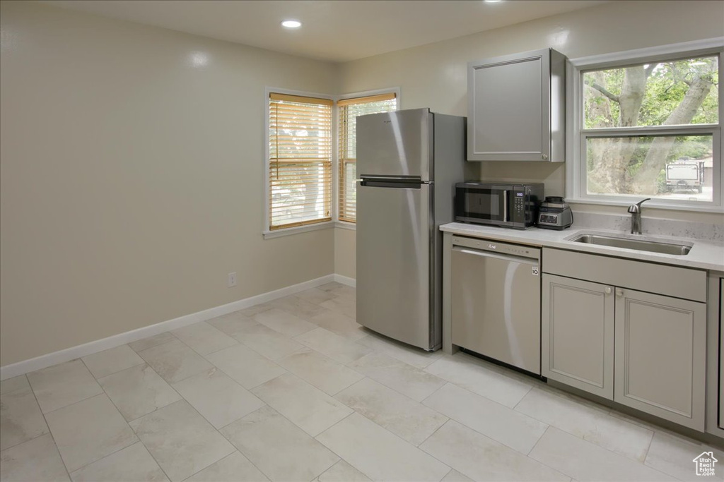 Kitchen featuring appliances with stainless steel finishes, a sink, gray cabinets, light countertops, and recessed lighting