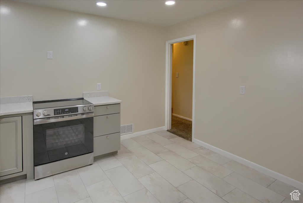 Kitchen with stainless steel range with electric cooktop, gray cabinets, light countertops, recessed lighting, and baseboards
