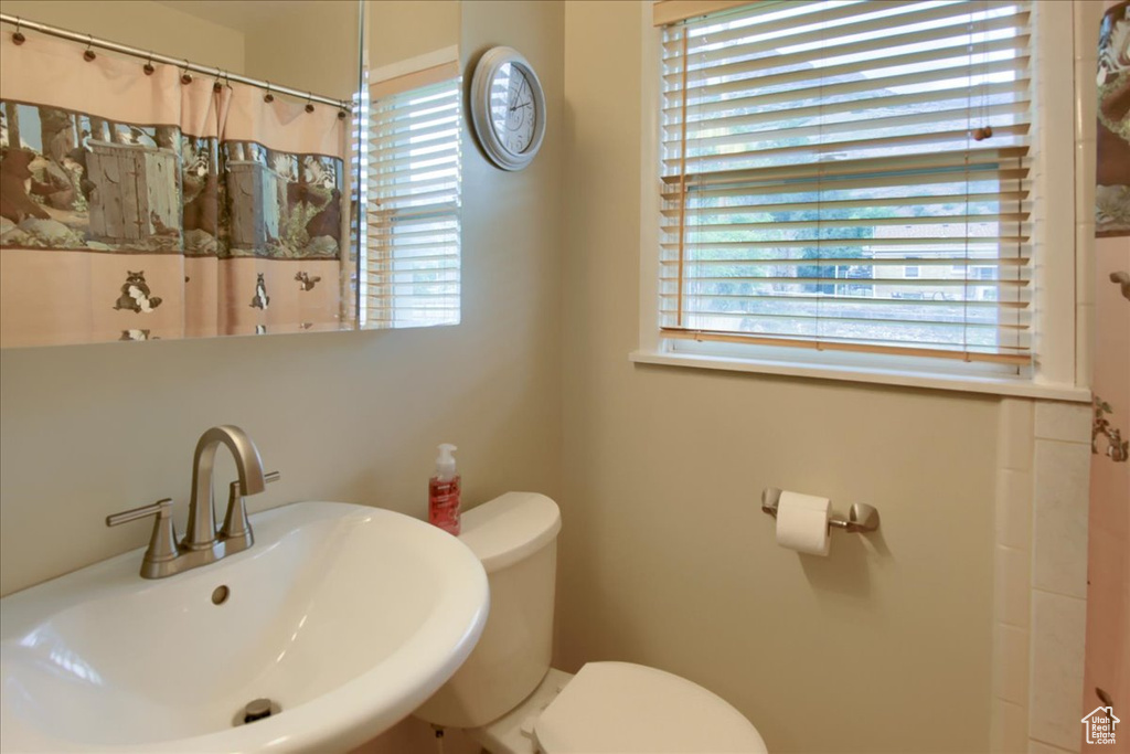 Bathroom with a sink, toilet, and curtained shower