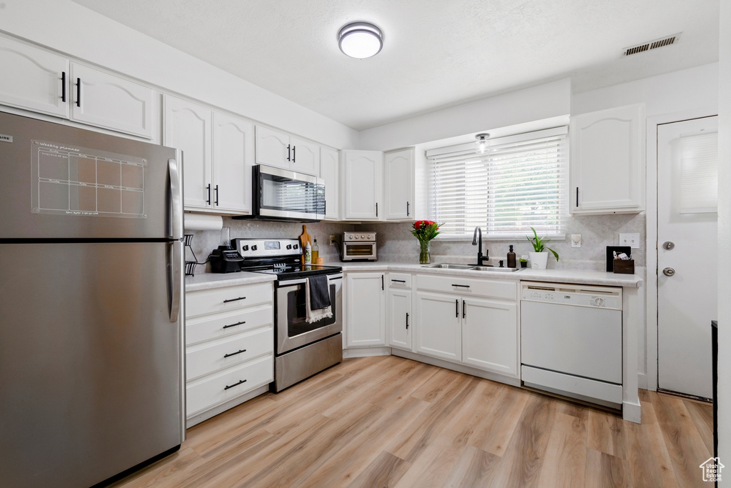 Kitchen featuring stainless steel appliances, a sink, white cabinetry, and tasteful backsplash