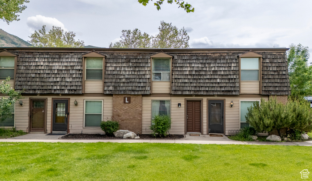 Townhome / multi-family property with mansard roof and a front lawn