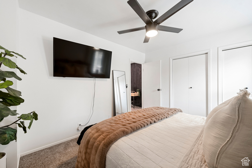 Carpeted bedroom with baseboards, multiple closets, and a ceiling fan