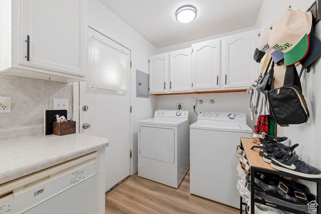 Laundry room with cabinet space, washer and clothes dryer, light wood-style floors, and electric panel