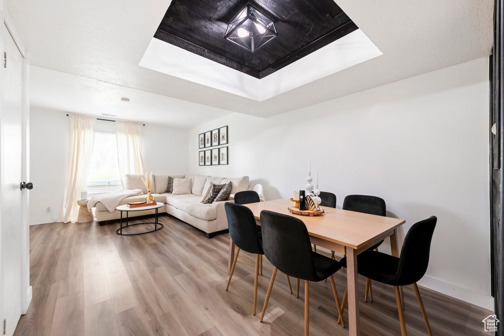 Dining room with a tray ceiling, wood finished floors, and baseboards