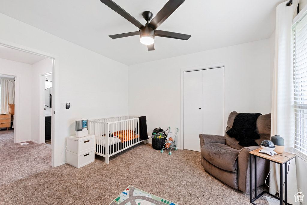 Bedroom with carpet, a closet, ceiling fan, and a crib