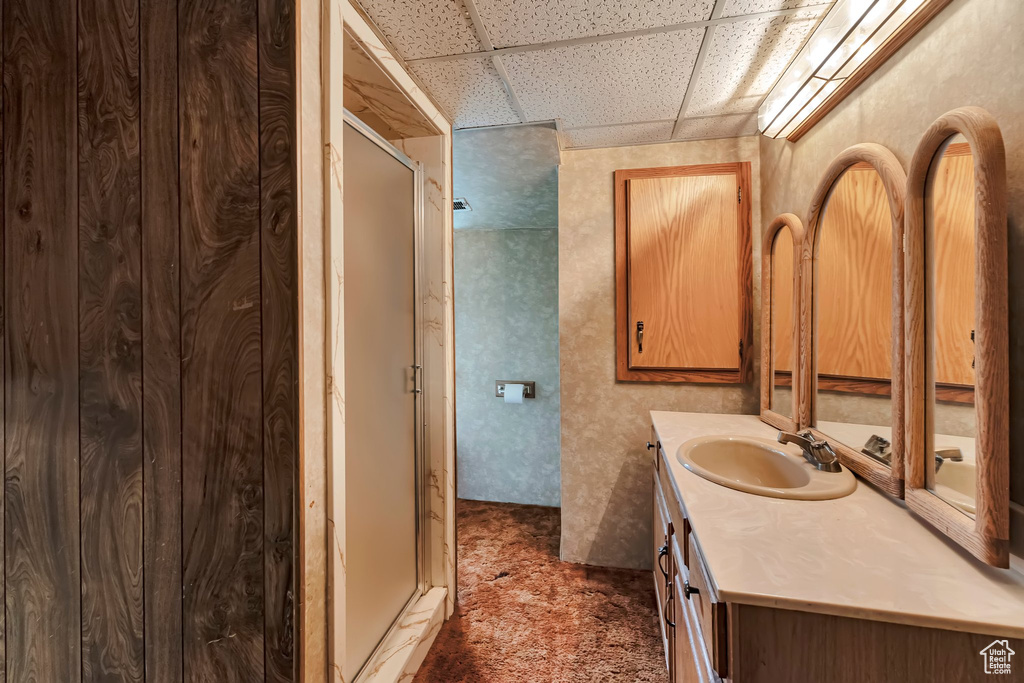 Bathroom featuring a drop ceiling, vanity, and a stall shower
