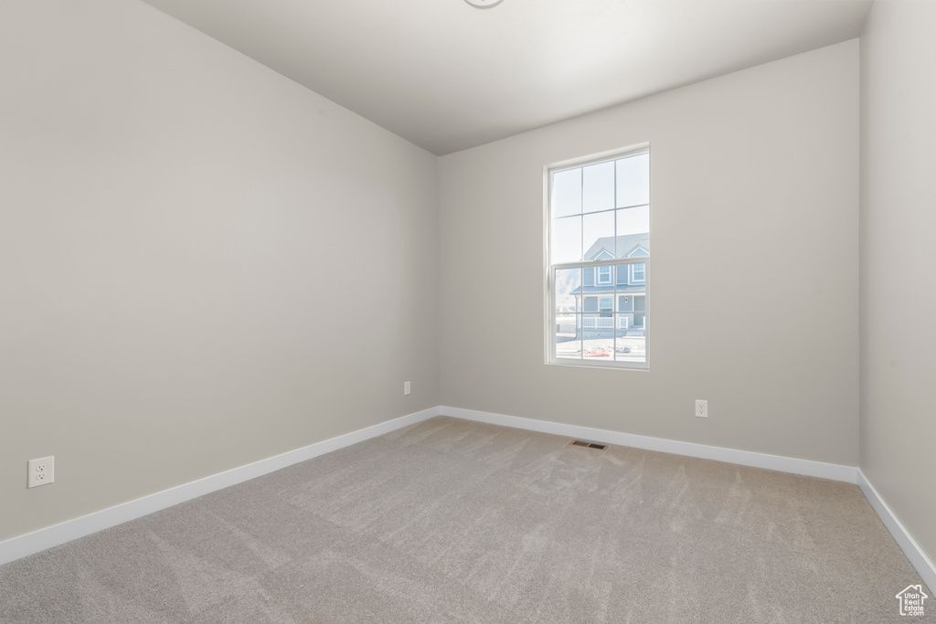 Spare room with light colored carpet, baseboards, and lofted ceiling