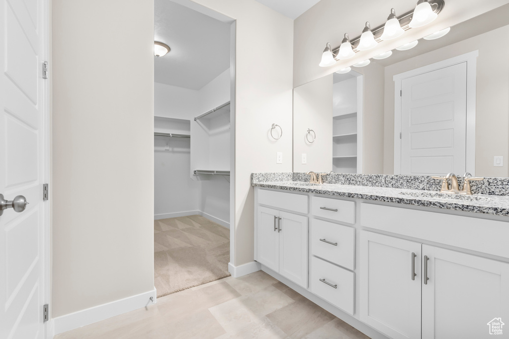 Full bathroom featuring double vanity, baseboards, and a spacious closet