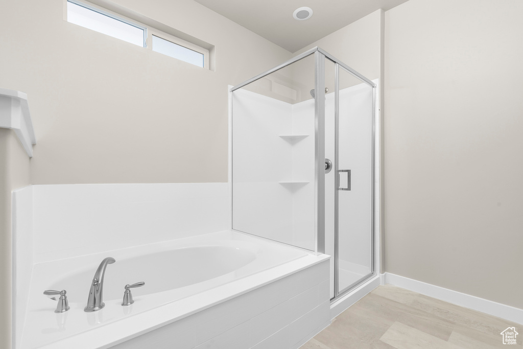 Full bath with wood finished floors, a stall shower, and a bath