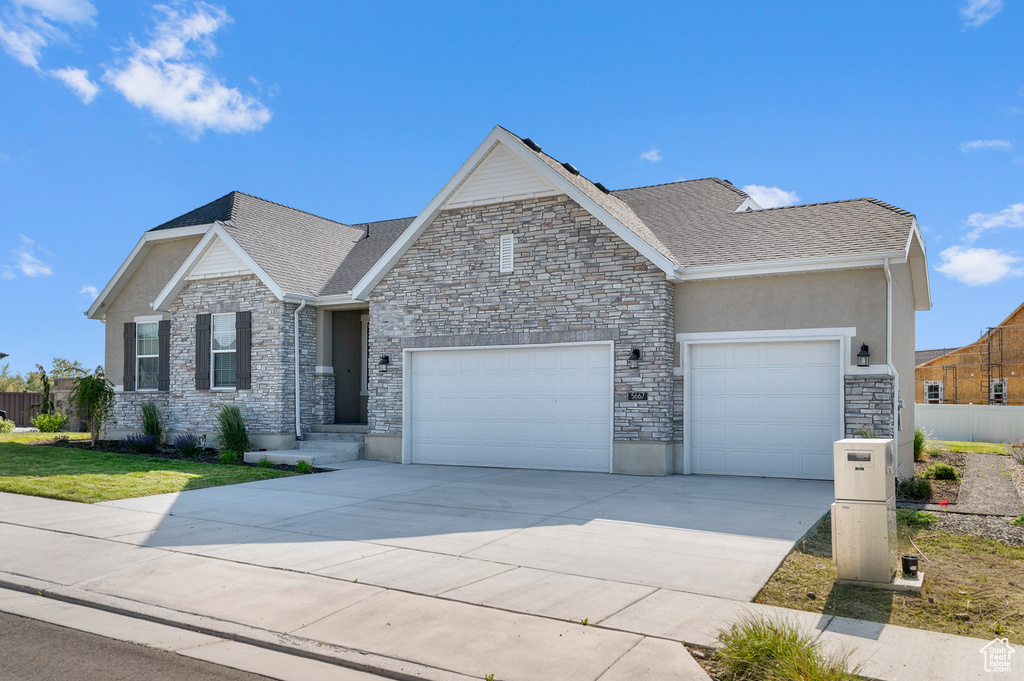 View of front of house featuring a garage, stone siding, and concrete driveway