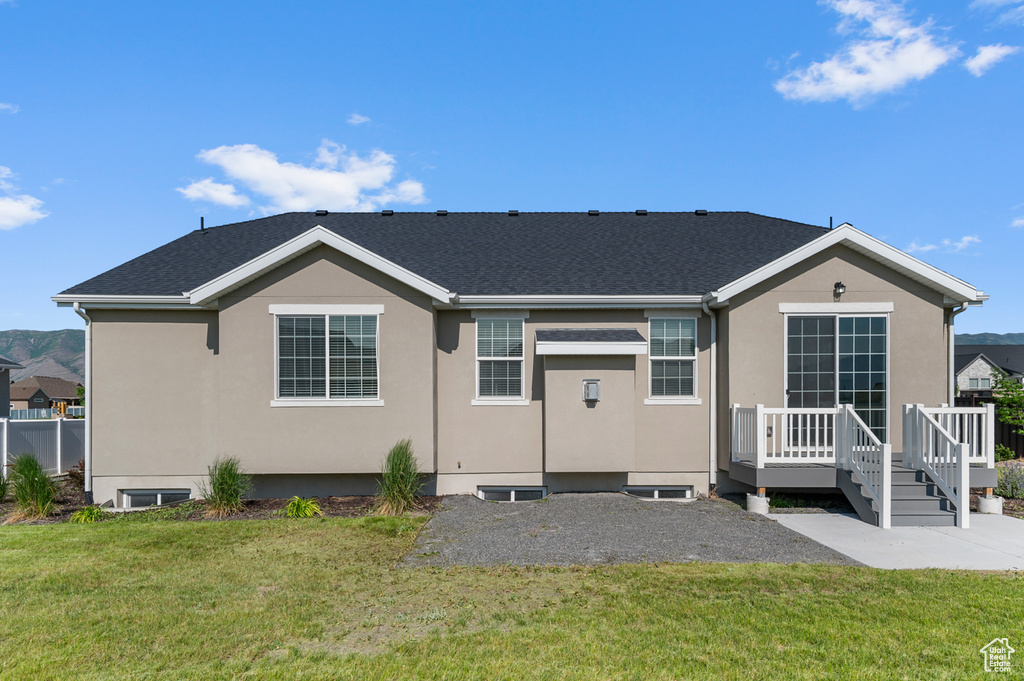 View of front of home with a deck, a front yard, stucco siding, and a patio area