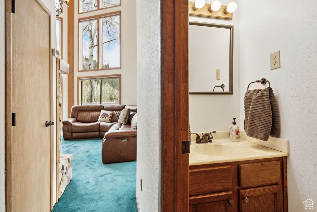 Bathroom featuring vanity, a textured wall, and a towering ceiling