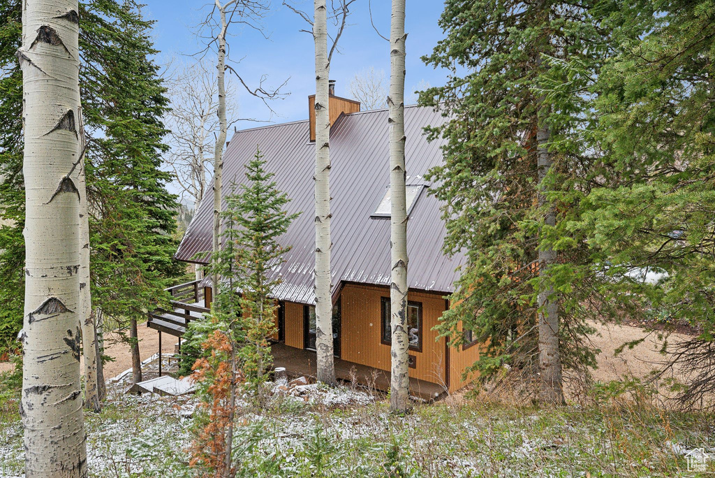 View of side of property featuring a chimney and metal roof