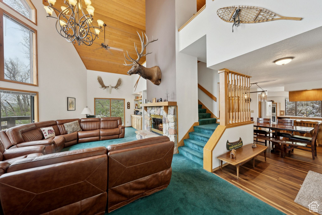 Living room with high vaulted ceiling, a chandelier, stairway, a fireplace, and wood finished floors