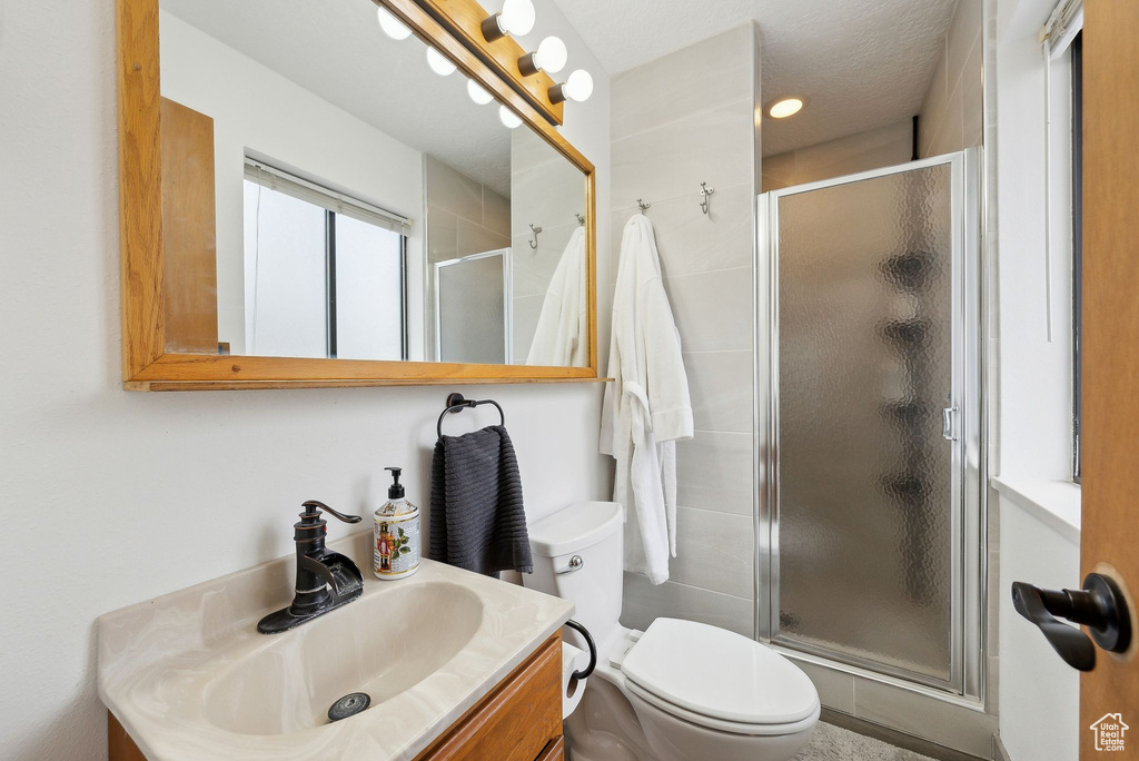 Bathroom with a shower stall, vanity, and toilet