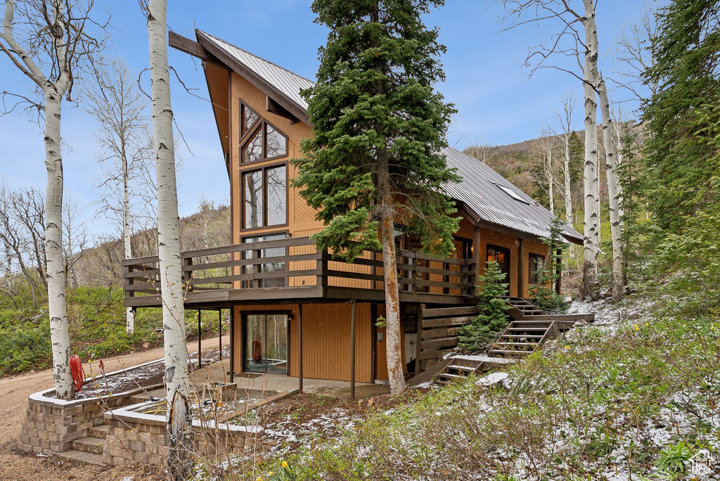 View of side of property with a wooden deck, metal roof, and stairway