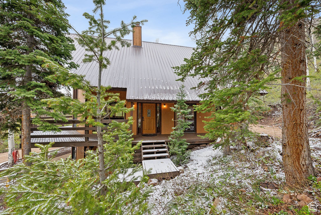 View of front facade with metal roof, a chimney, and a porch