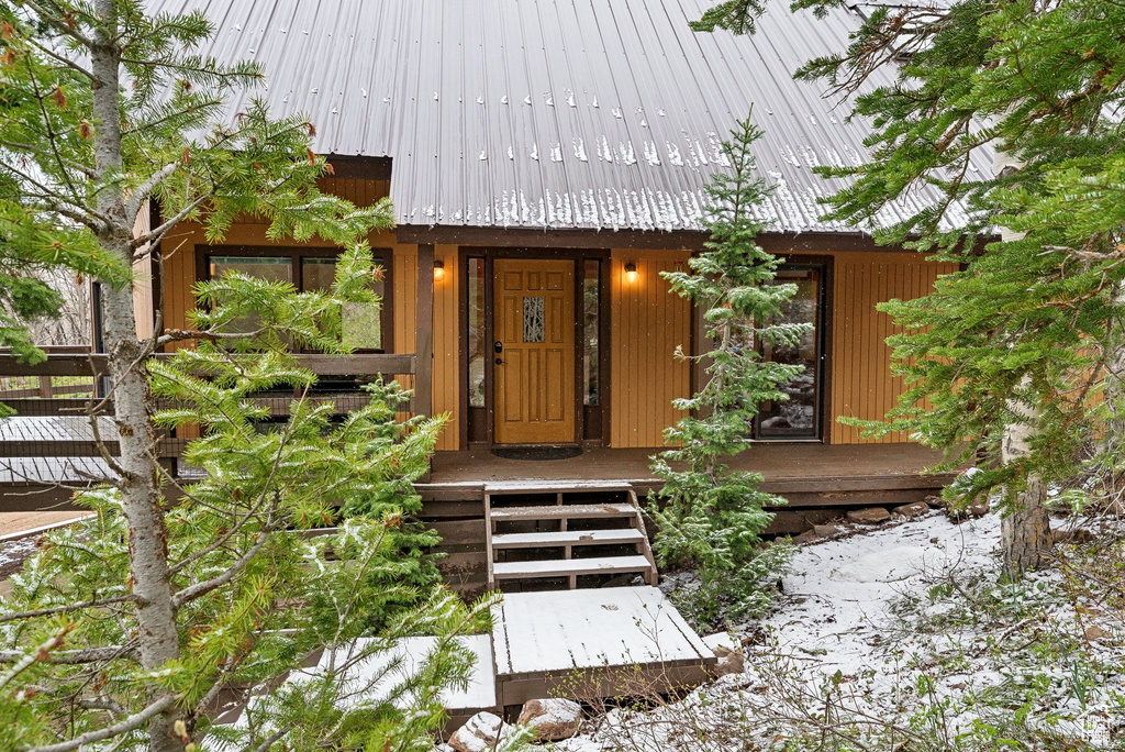 View of exterior entry featuring metal roof and covered porch