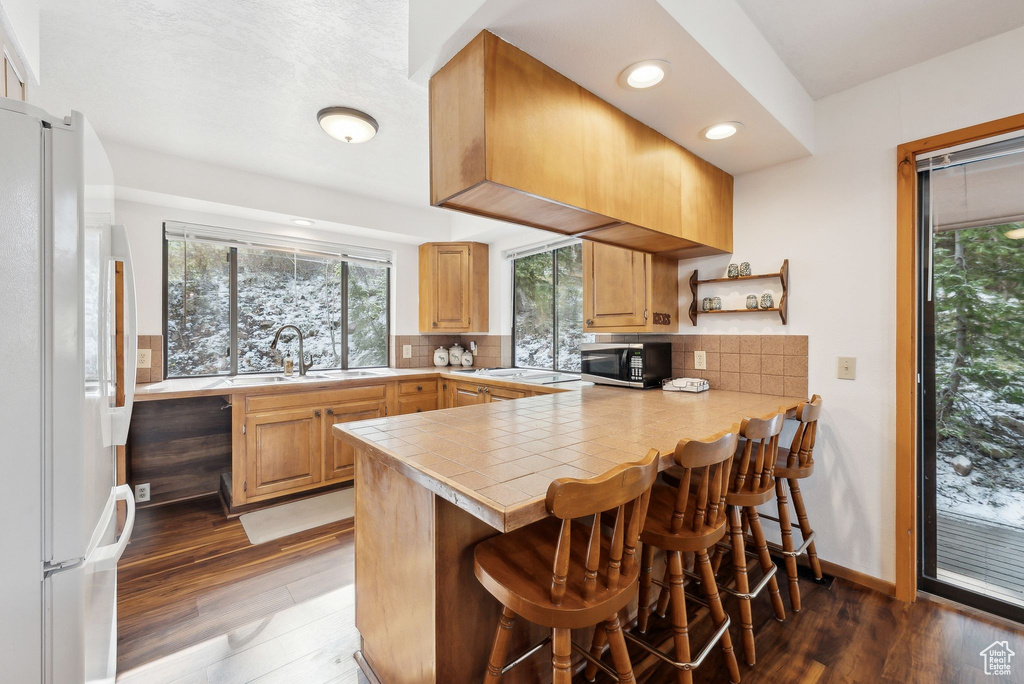 Kitchen with white appliances, a sink, plenty of natural light, a kitchen bar, and recessed lighting