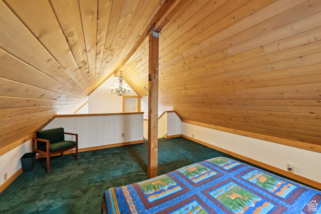 Carpeted bedroom with wood ceiling, a chandelier, vaulted ceiling, baseboards, and wooden walls