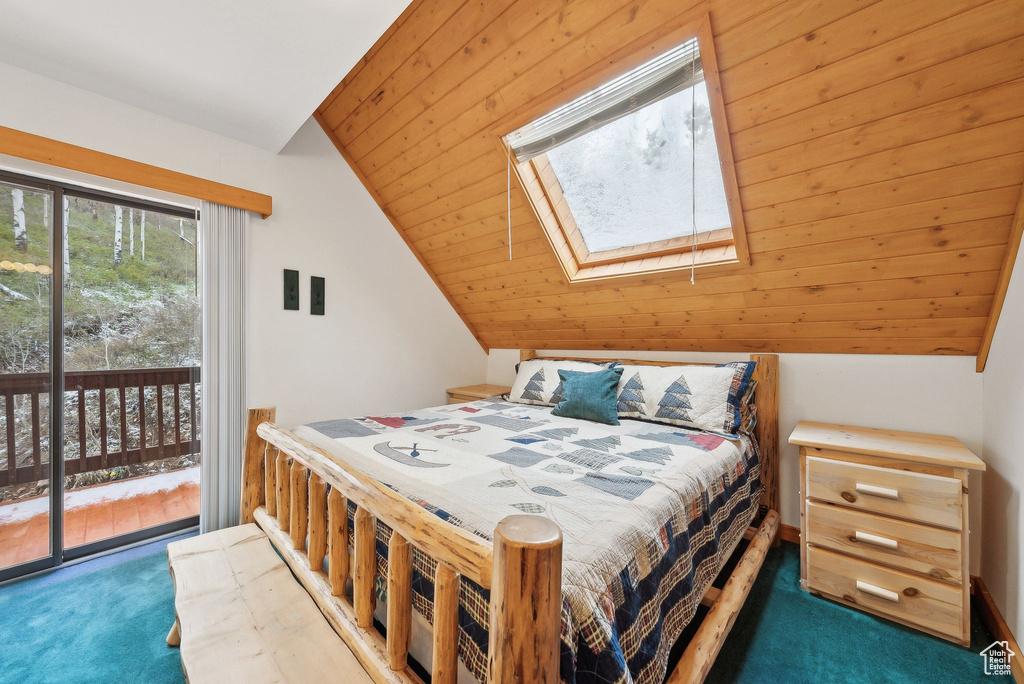 Carpeted bedroom featuring access to exterior, a skylight, and lofted ceiling