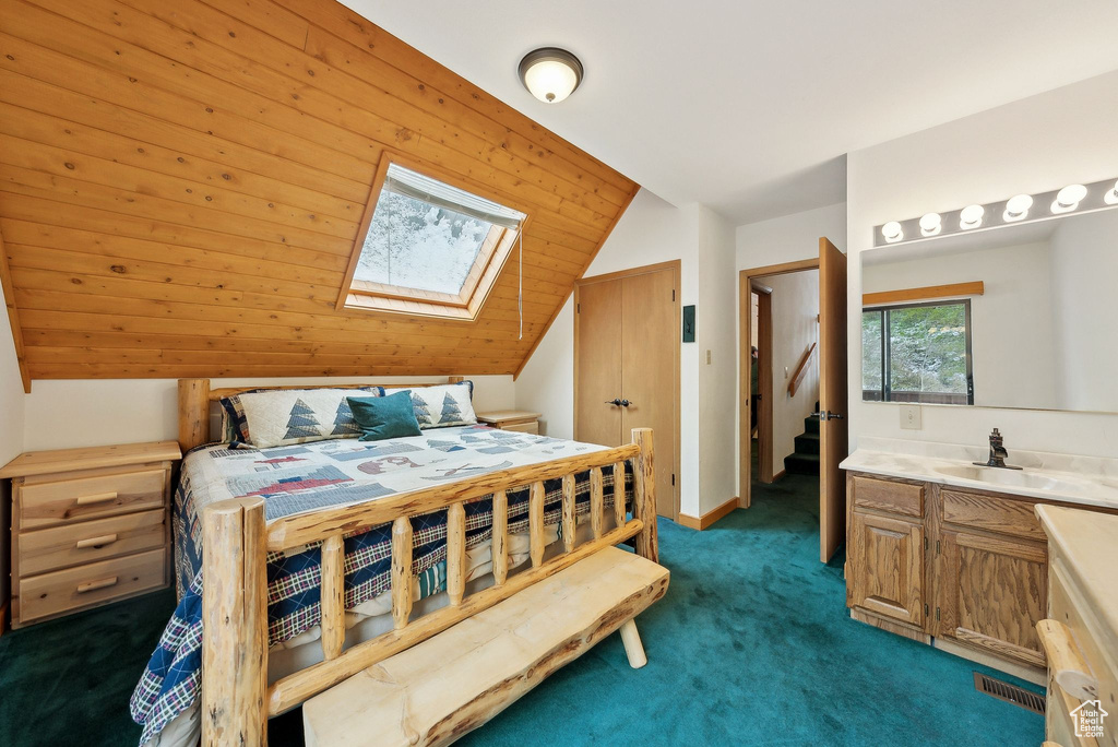 Bedroom featuring lofted ceiling, a skylight, a sink, and carpet flooring