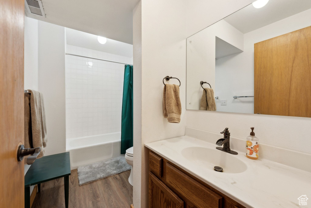 Bathroom featuring toilet, wood finished floors, vanity, and shower / tub combo