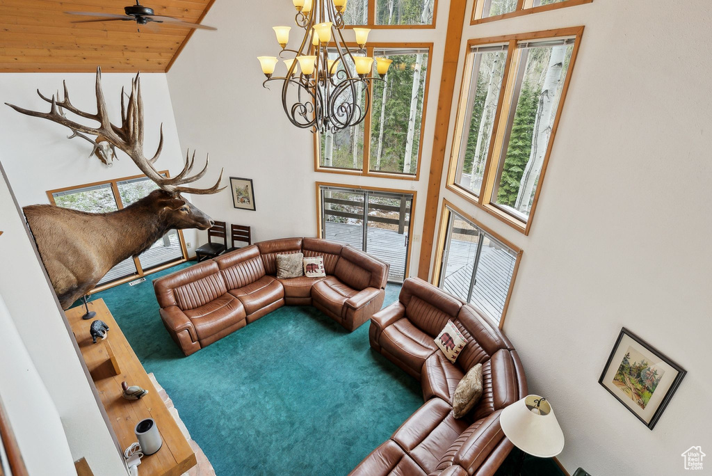Living area featuring a towering ceiling, carpet floors, healthy amount of natural light, a chandelier, and a ceiling fan