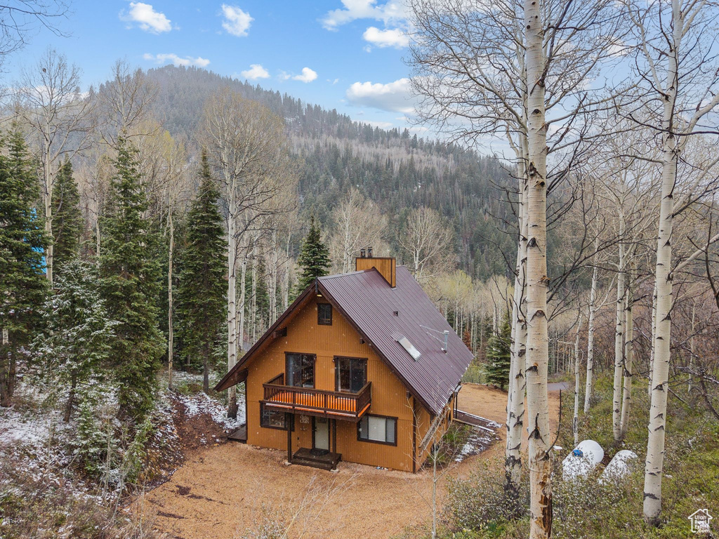 Rear view of property featuring a wooded view, metal roof, and a deck with mountain view