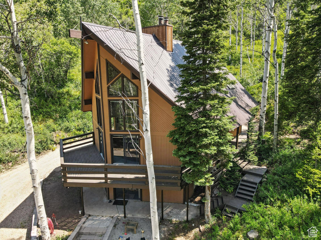 Rear view of house with a chimney, a metal roof, stairs, and a wooden deck