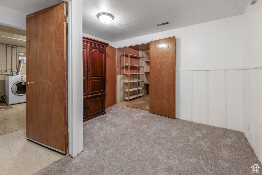 Unfurnished bedroom with washer / clothes dryer, wainscoting, and a decorative wall