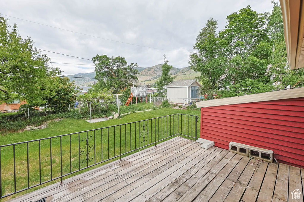 Wooden deck featuring a playground and a mountain view