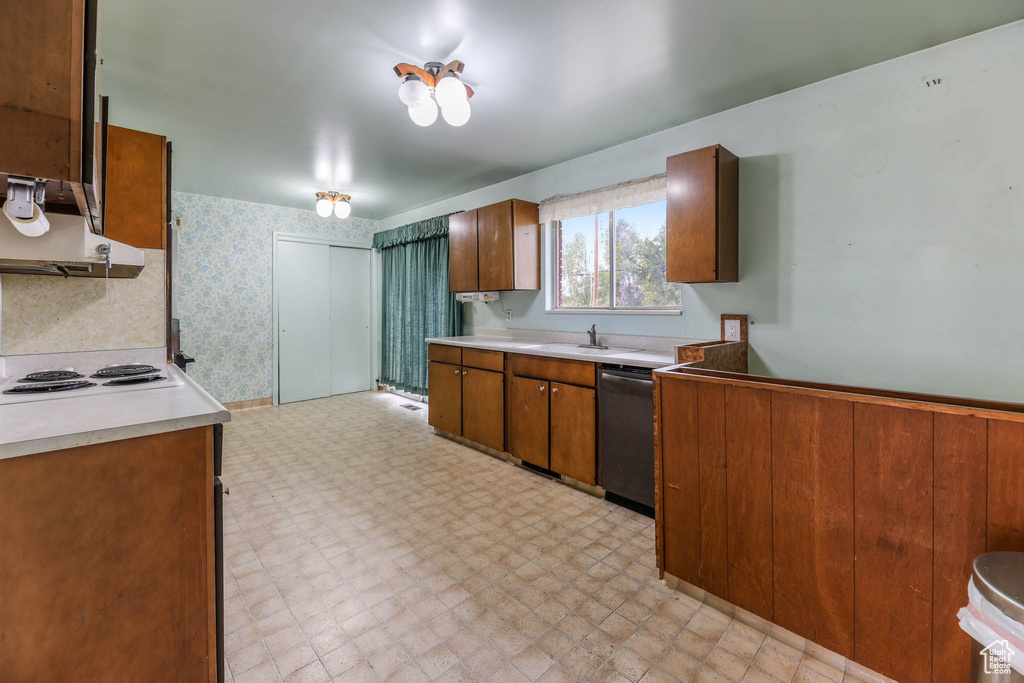 Kitchen featuring dishwashing machine, light floors, under cabinet range hood, a sink, and brown cabinets