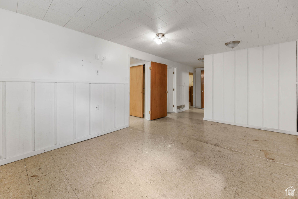 Spare room with a decorative wall, tile patterned floors, and wainscoting