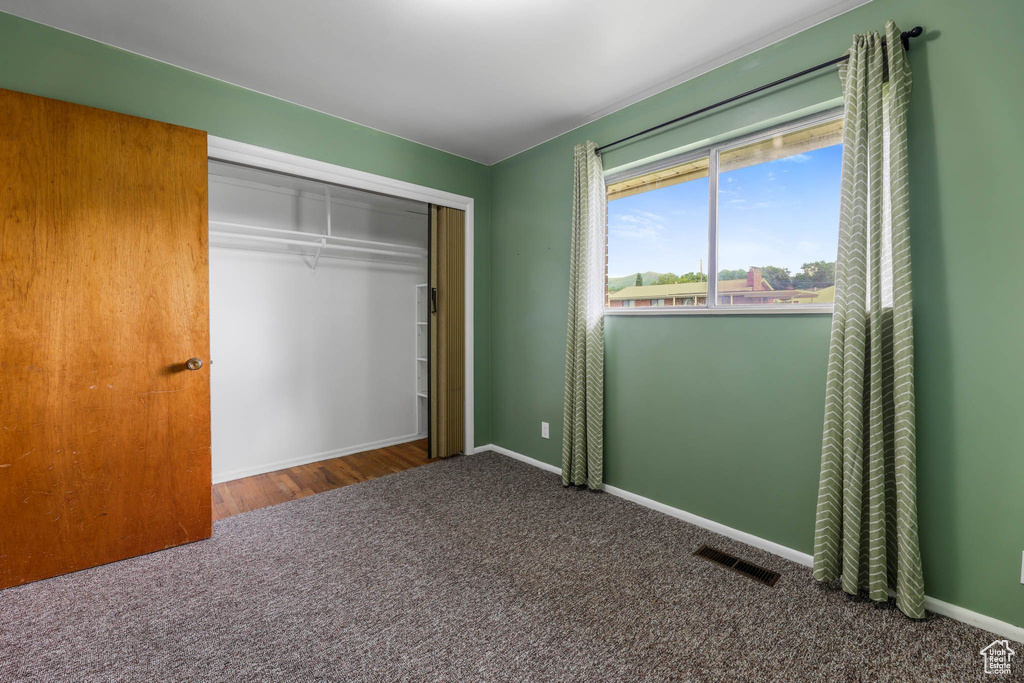 Unfurnished bedroom with carpet, a closet, and baseboards