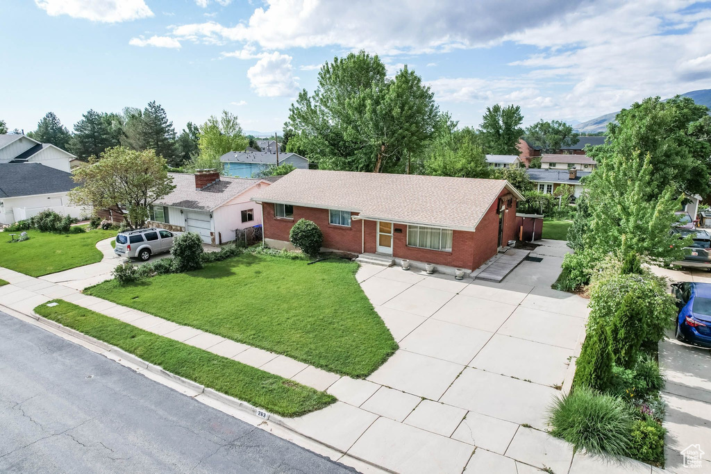 Ranch-style home featuring brick siding, driveway, a front yard, roof with shingles, and a residential view