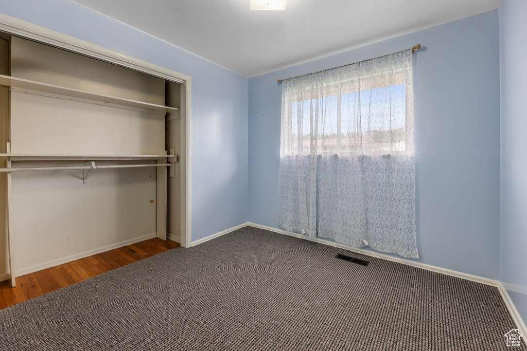 Unfurnished bedroom featuring wood finished floors, a closet, and baseboards