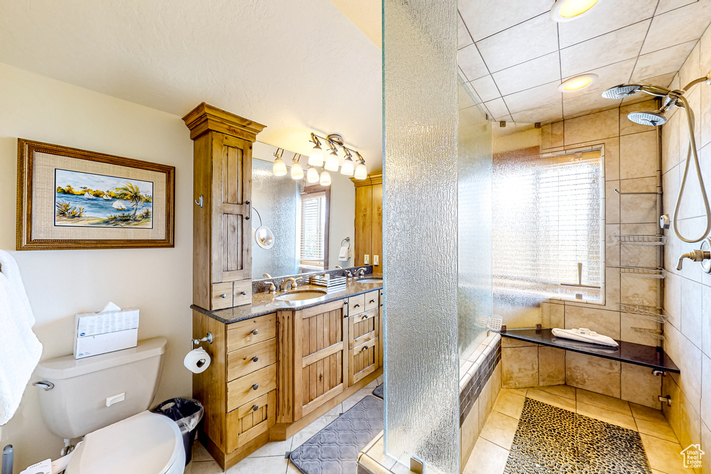 Full bath featuring a tile shower, toilet, tile patterned floors, and vanity