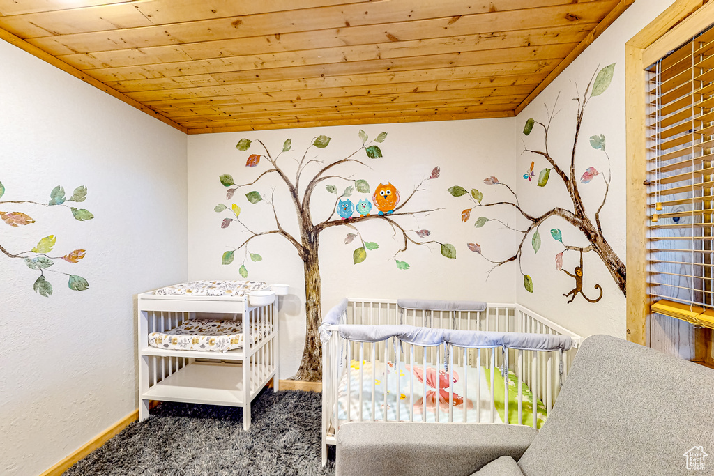 Bedroom with wood ceiling, carpet flooring, a crib, and baseboards